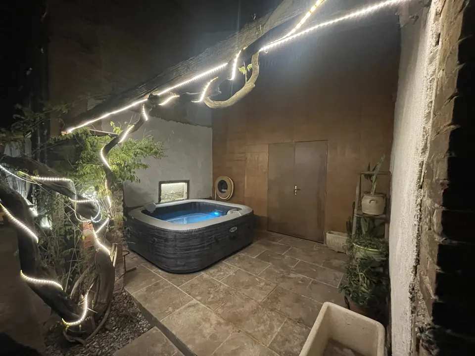 Le spa de nuit sur sa dalle carrelée, éclairé par une guirlande LED.