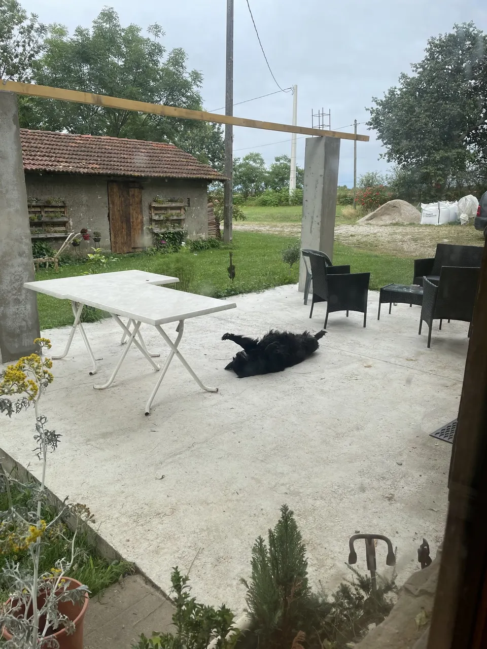 Dalle béton terminée, poteau en place et poutre bois posée au-dessus.