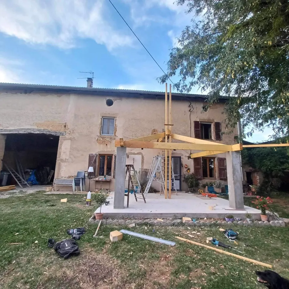 Ossature de la charpente en croupe montée sur les poteaux, échelle en place.