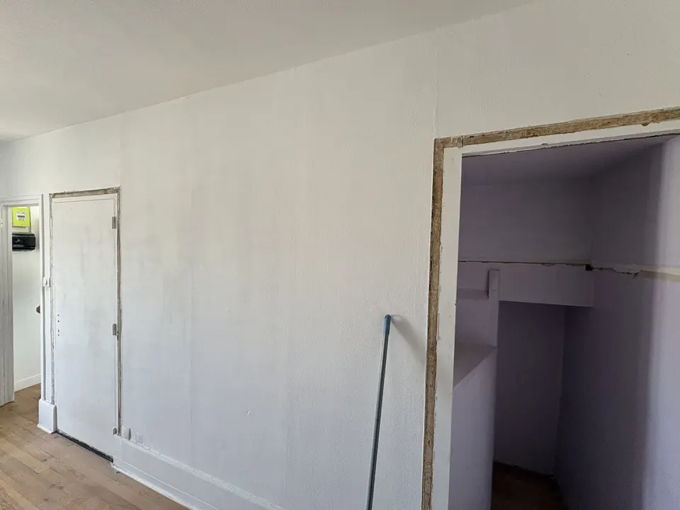 Avant les travaux : mur blanc avec une porte et une ouverture sur un placard.