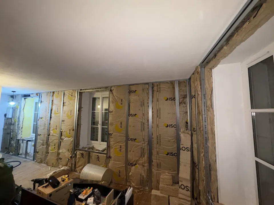 Pose de l'isolant entre les montants métalliques de la cloison.