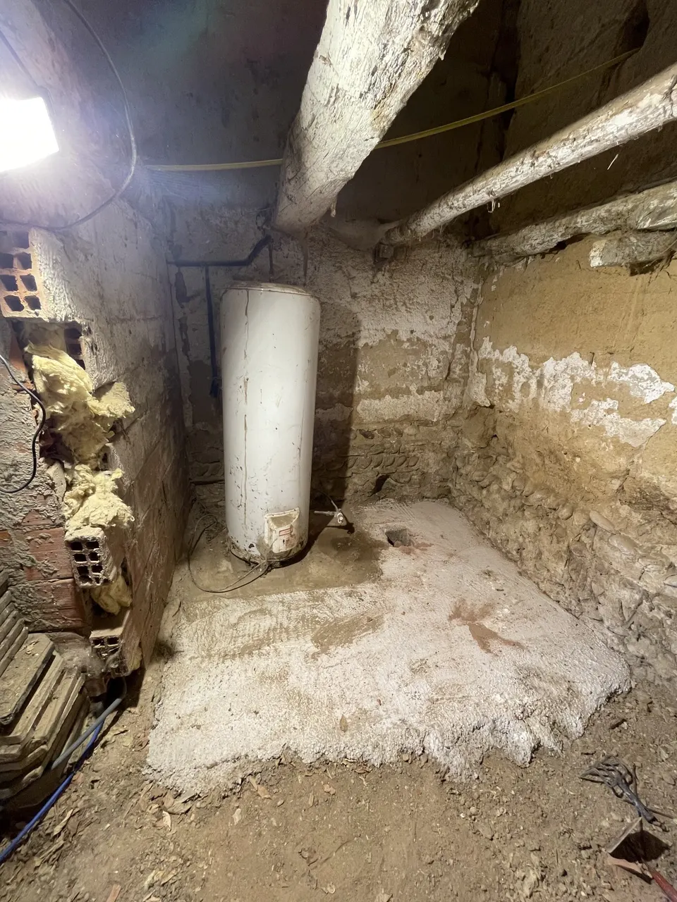 Début du chantier : ballon d'eau chaude et dalle brute dans la cave en pierre
