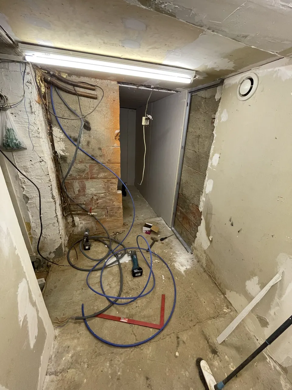 Câbles et tuyaux en attente dans le couloir, plaques de plâtre posées