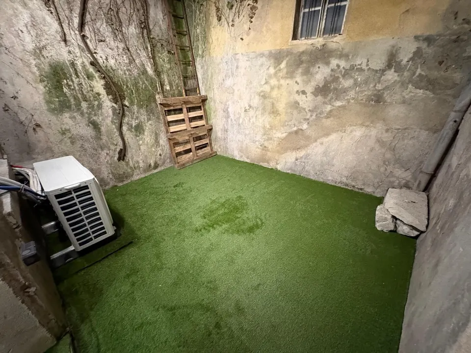 Le gazon synthétique est déroulé sur le sol de la cour, les murs restent à traiter.