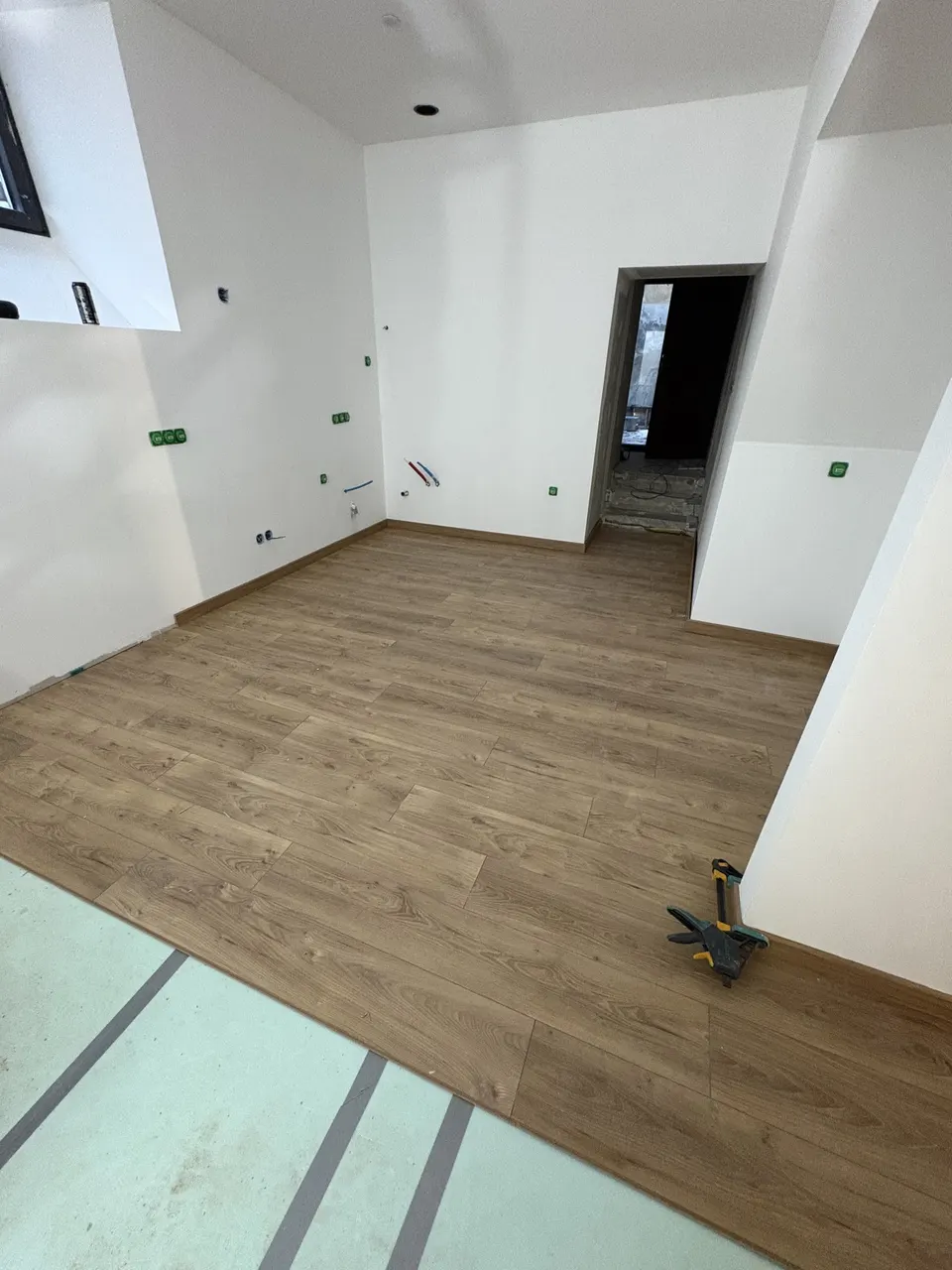 Pose du parquet stratifié dans le séjour, la sous-couche est encore visible au sol.