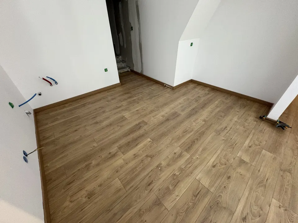 Séjour : parquet posé jusqu'aux plinthes, avec les attentes d'eau au mur.