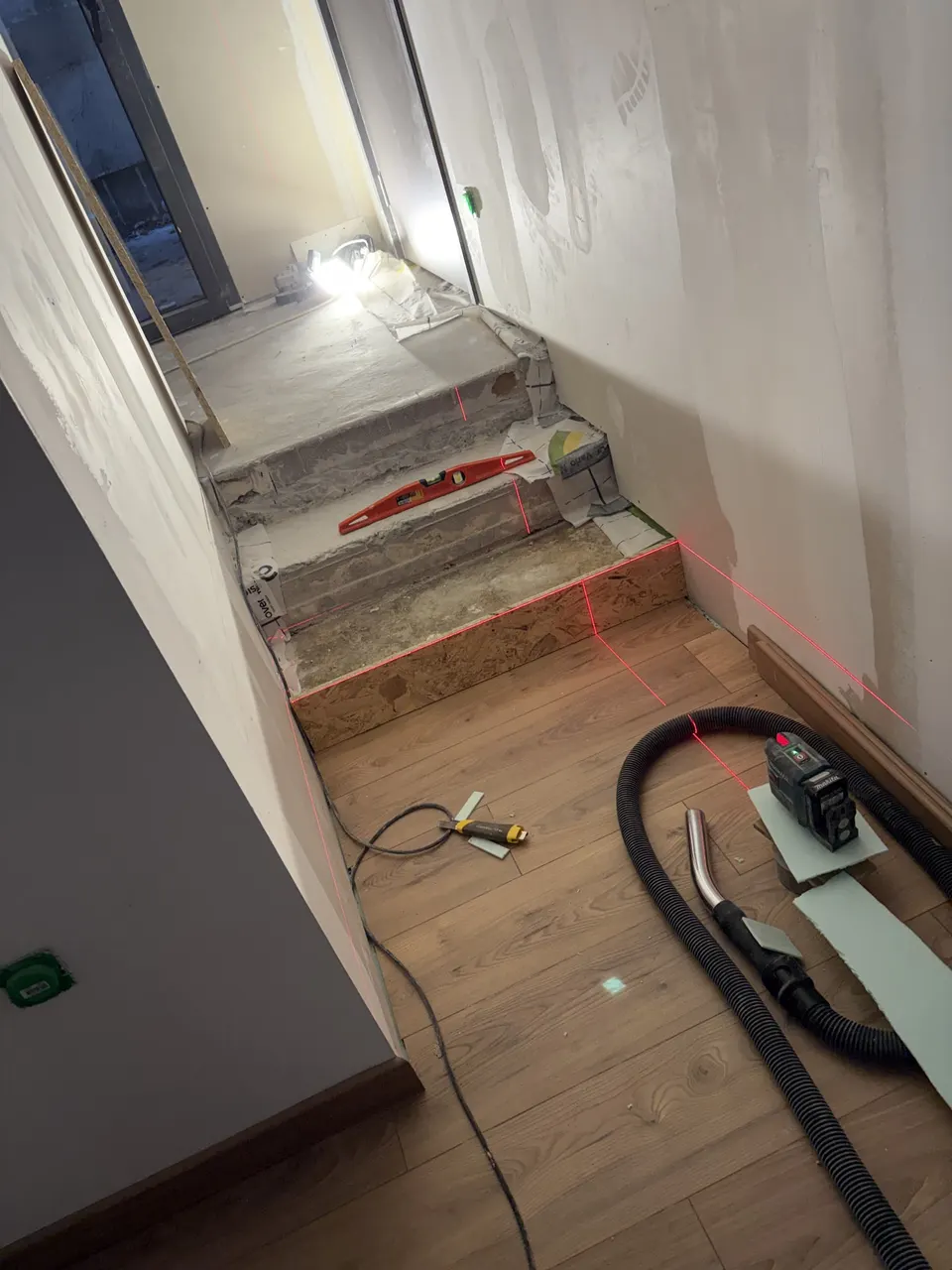 Escalier en cours de finition : niveau, laser et aspirateur de chantier.