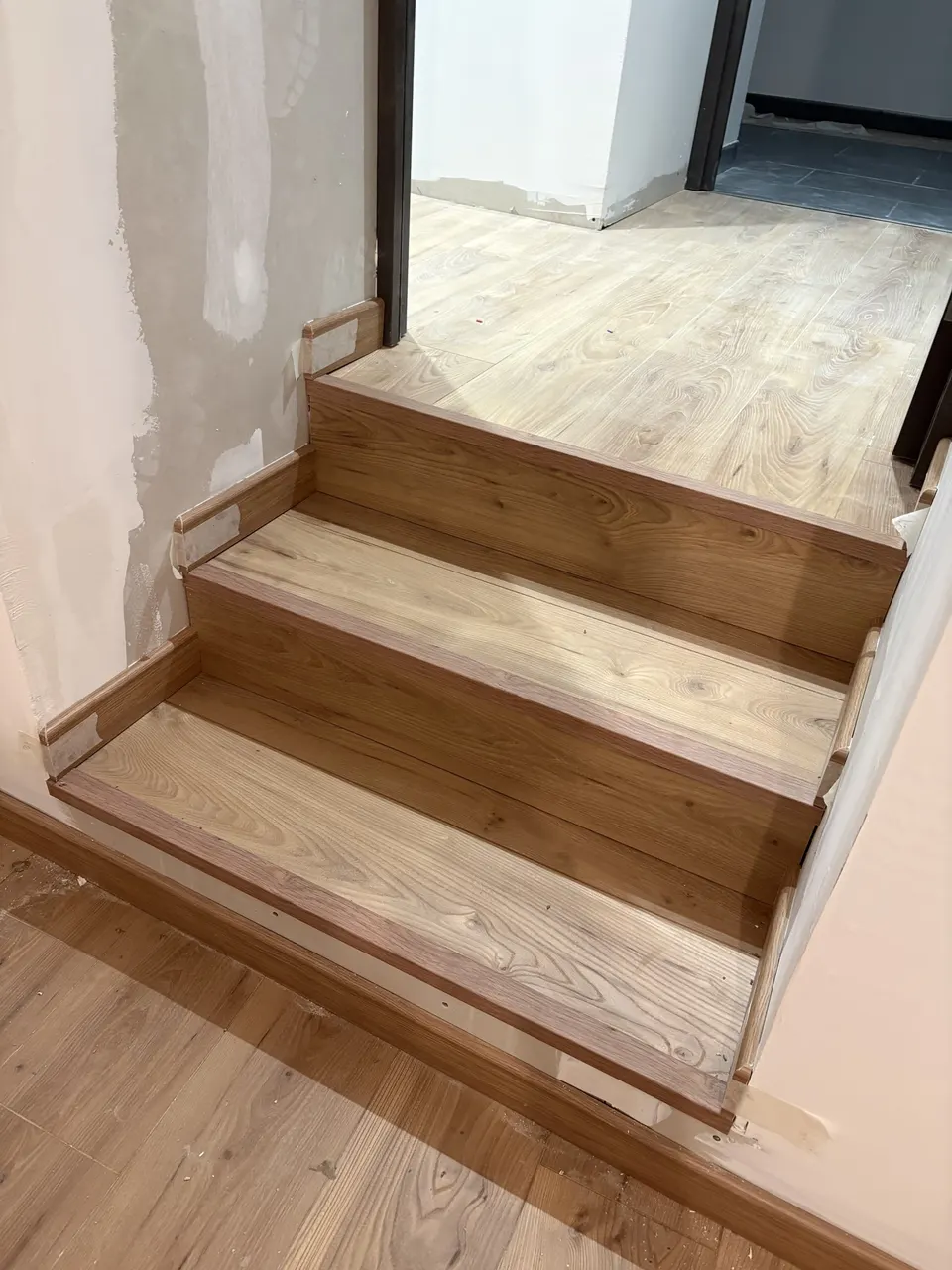 Marches de l'escalier habillées de parquet stratifié, plinthes en cours de pose.