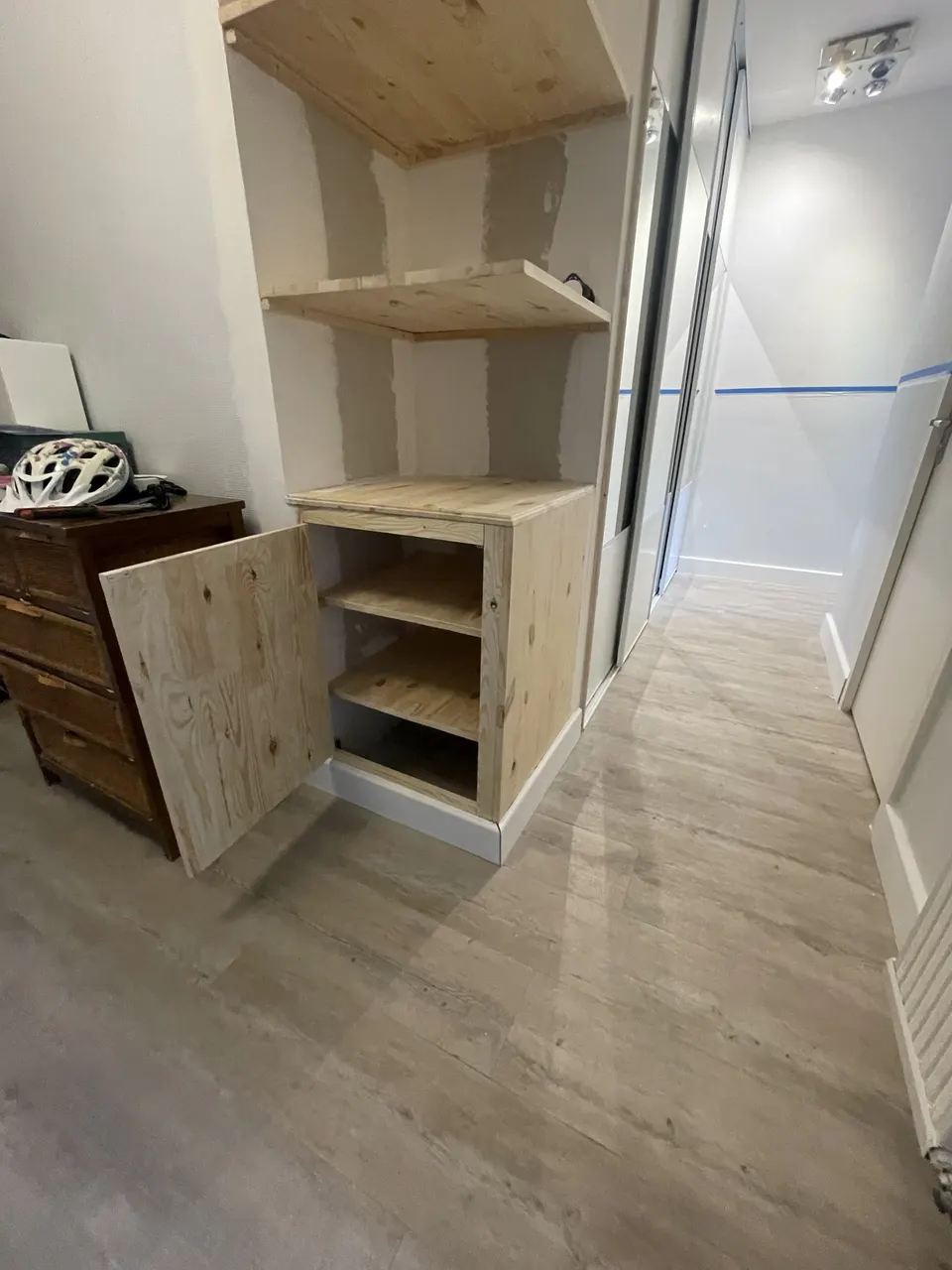 Meuble bas en bois brut avec sa porte ouverte et ses étagères intérieures.