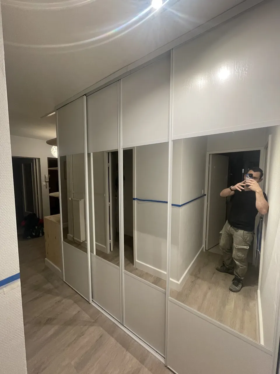 Portes coulissantes à panneaux blancs et miroirs posées sur toute la longueur.