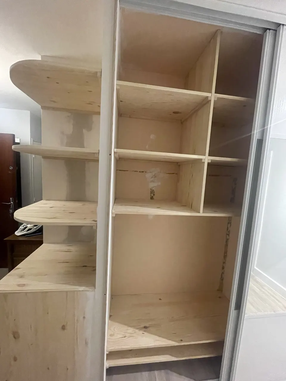 Rangements à compartiments en bois brut, à côté des étagères d'angle arrondies.