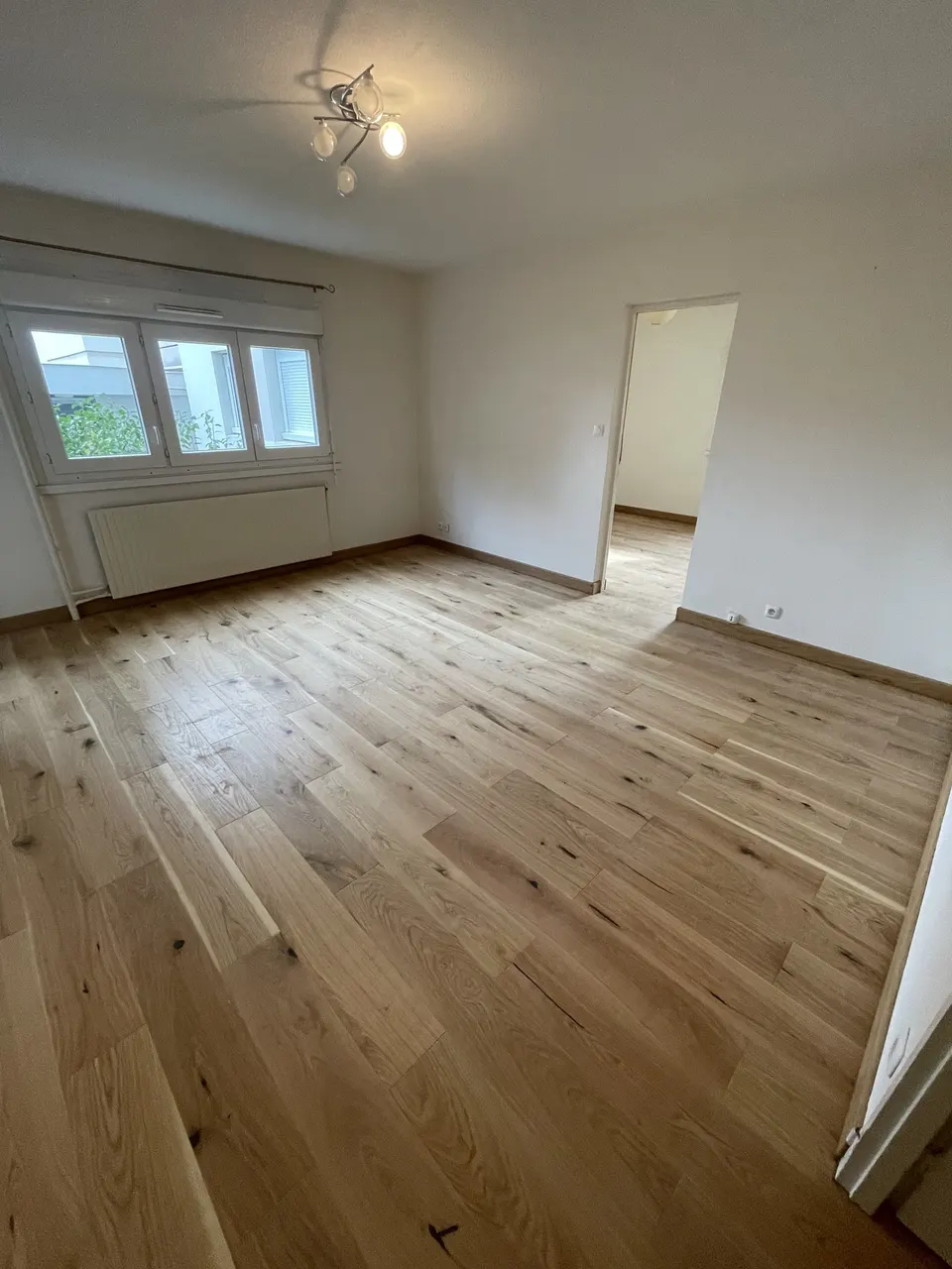 Salon terminé : parquet en chêne posé, vue vers la fenêtre et la porte ouverte