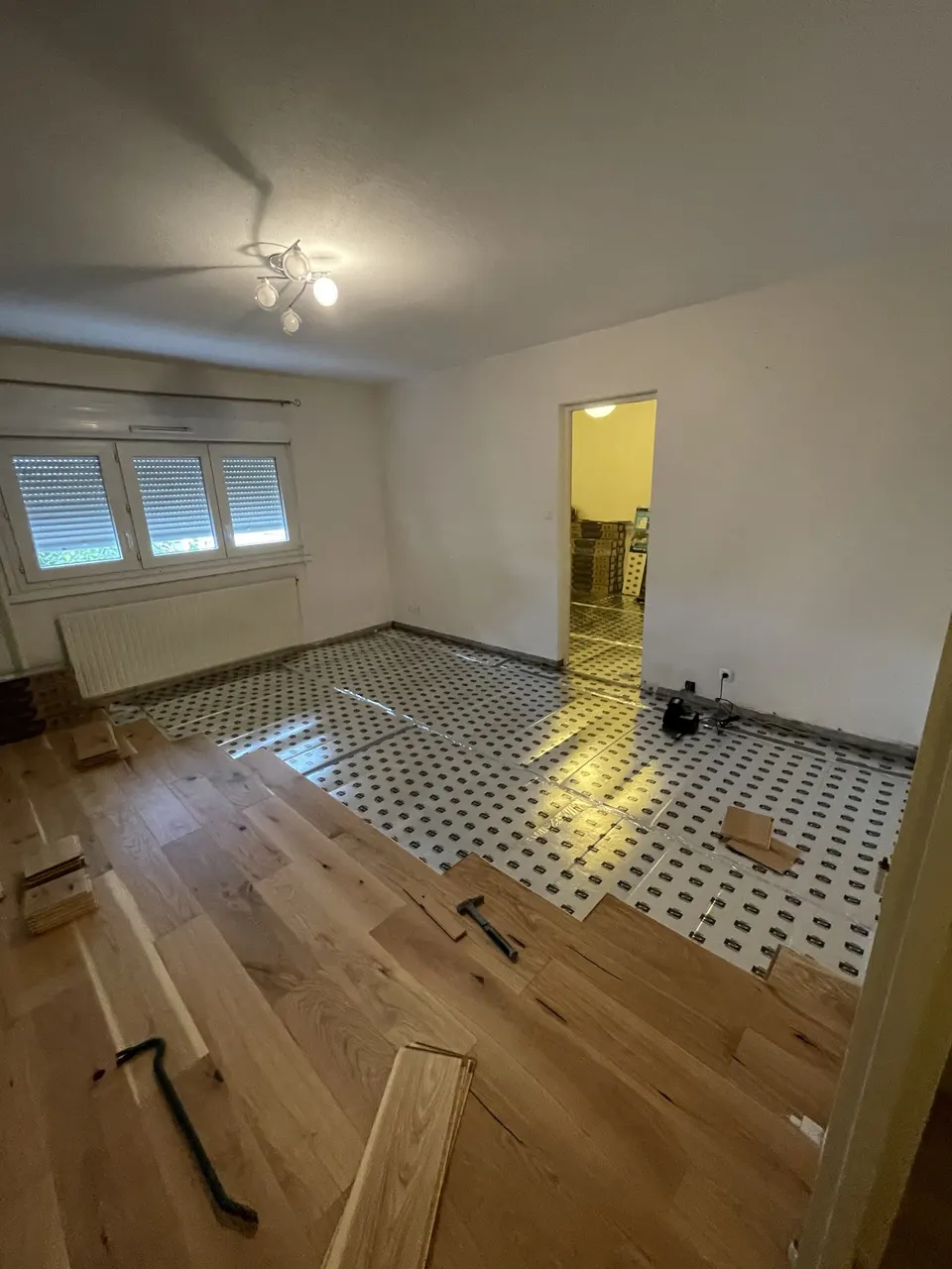 Pose en cours dans le salon : sous-couche en place, parquet à moitié posé
