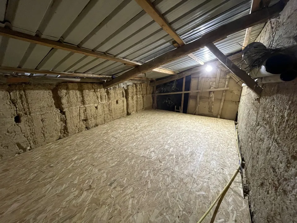 Plancher OSB terminé sous la toiture en tôle, entre les murs en terre.