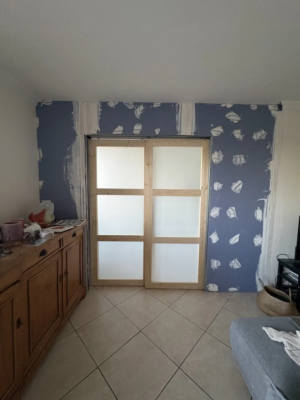 La porte fermée dans la cloison, papier peint encore partiellement en place