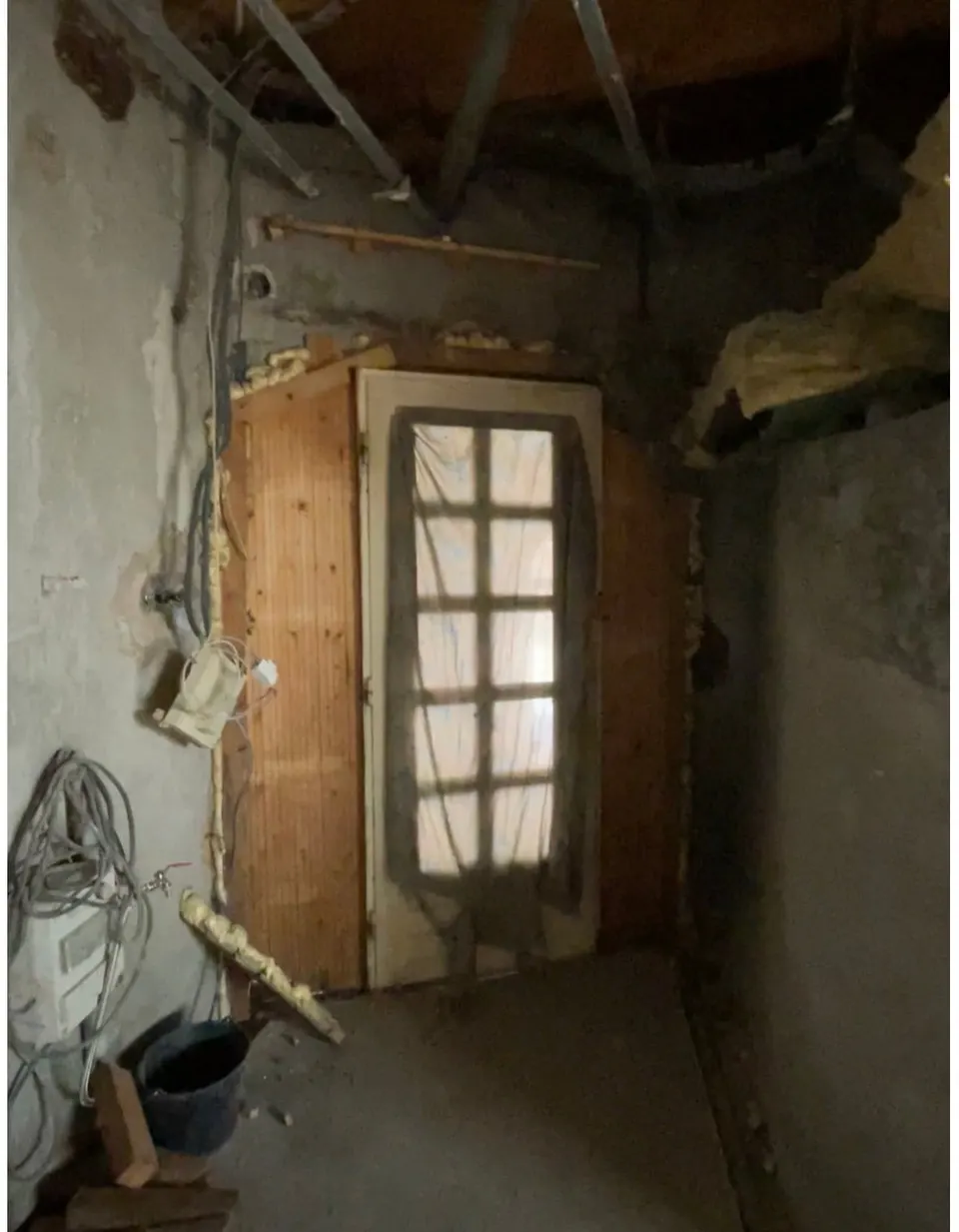 L'entrée côté intérieur en cours de travaux, avec l'ancienne porte et les câbles.