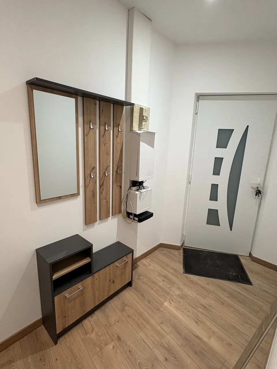 Le hall terminé : porte blanche, miroir, porte-manteaux et meuble bas.