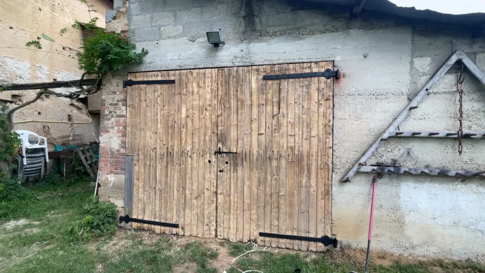 Porte de grange à deux battants en bois clair, vue d'ensemble de la façade