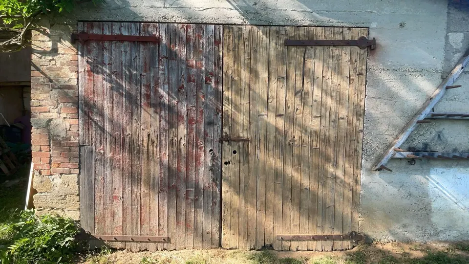 Porte à deux battants en planches usées, traces de peinture rouge