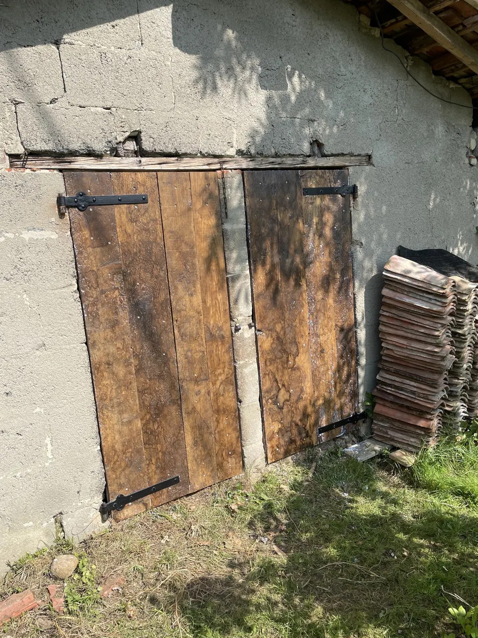 Porte de grange en bois sombre à deux battants, ferrures noires