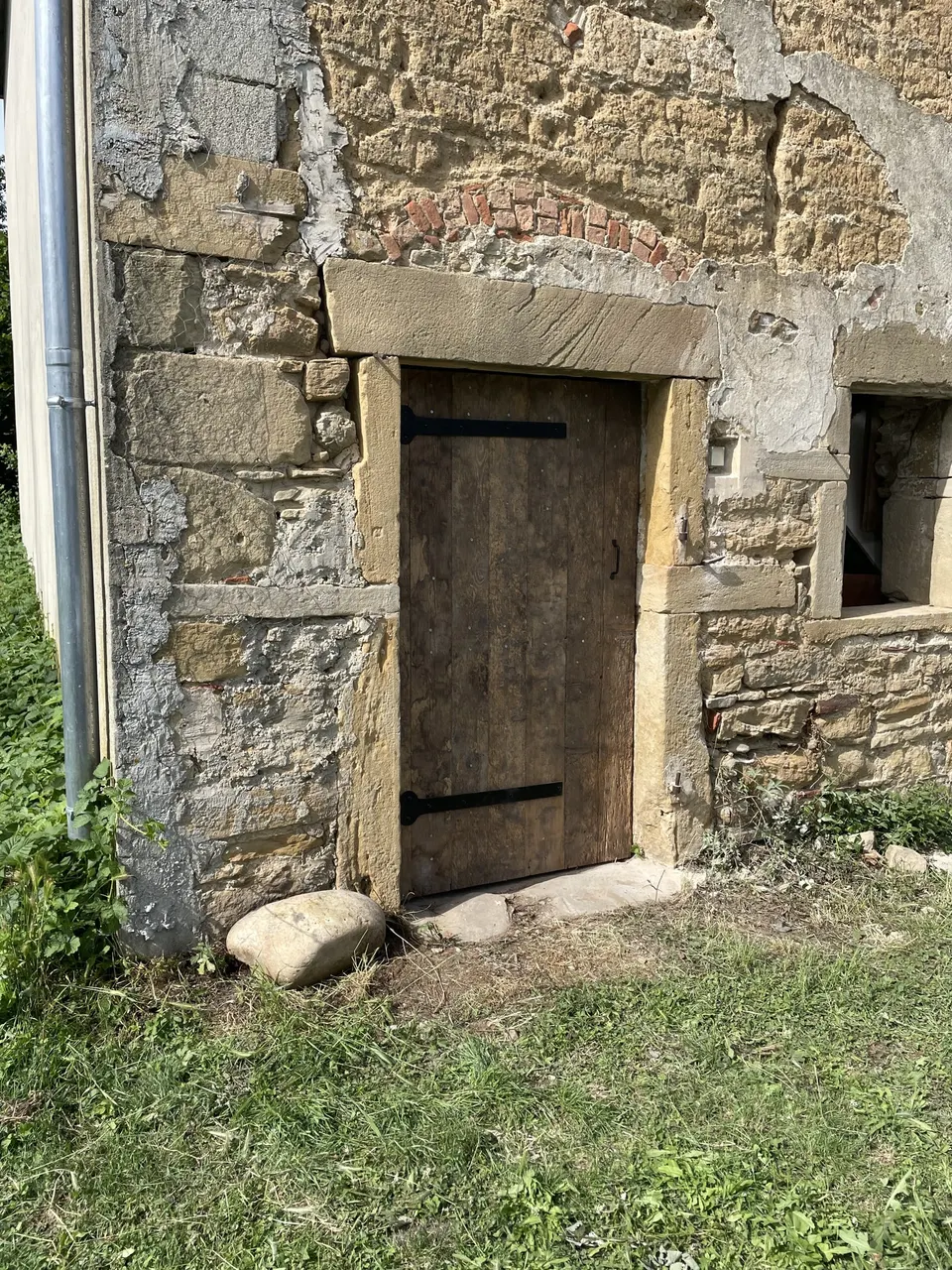 Porte en planches neuves dans son encadrement de pierre, fenêtre dégagée