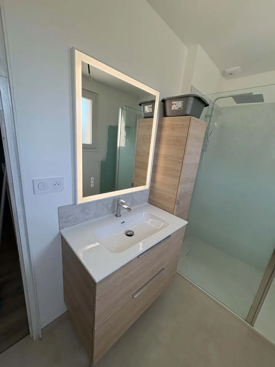 Salle de bain terminée : meuble vasque, miroir lumineux et douche avec paroi vitrée