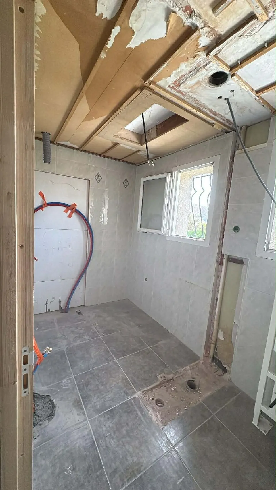 Salle de bain avant travaux : plafond déposé et ancien carrelage au sol