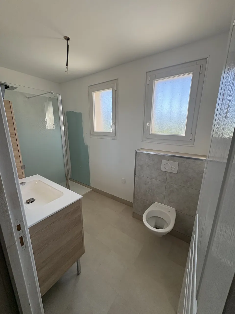 Salle de bain terminée : WC suspendu, carrelage au sol et meuble vasque