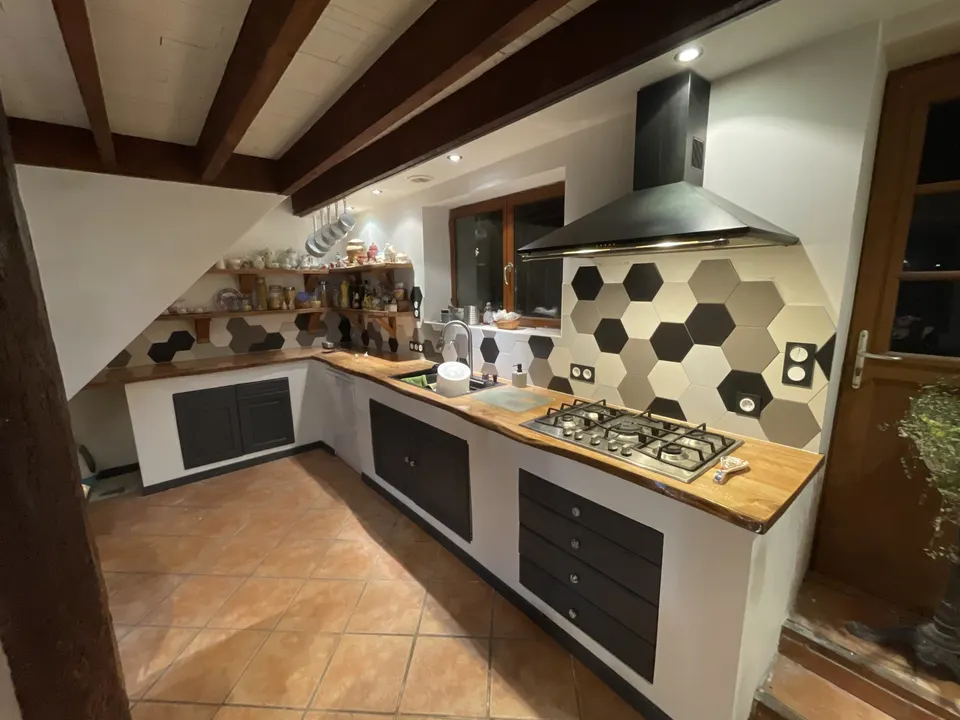 Cuisine terminée : crédence hexagonale, plan de travail en bois et plaque de cuisson.
