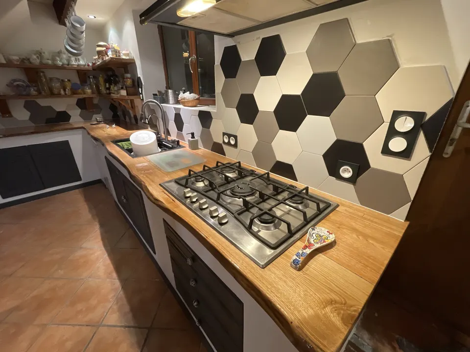 Crédence en hexagones noirs, gris et blancs derrière la plaque de cuisson.