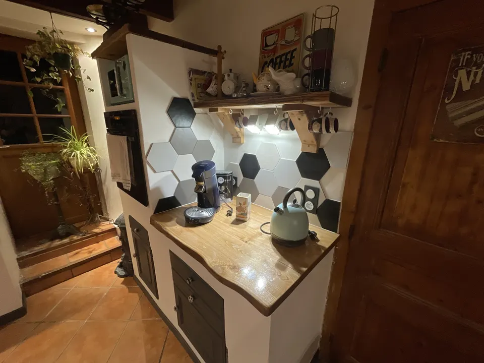 Coin café : plan de travail en bois, four encastré et étagère en bois.