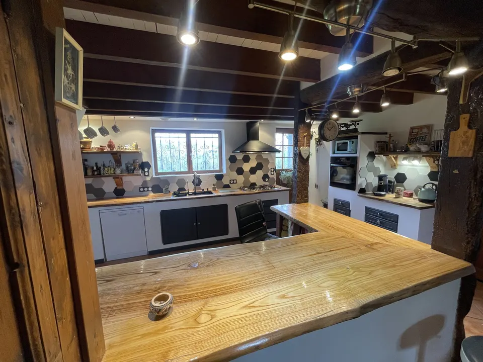 Bar en bois verni ouvert sur la cuisine, vu depuis la pièce de vie.