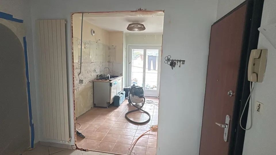 Dépose de la cuisine : ouverture dans le mur, aspirateur de chantier au sol