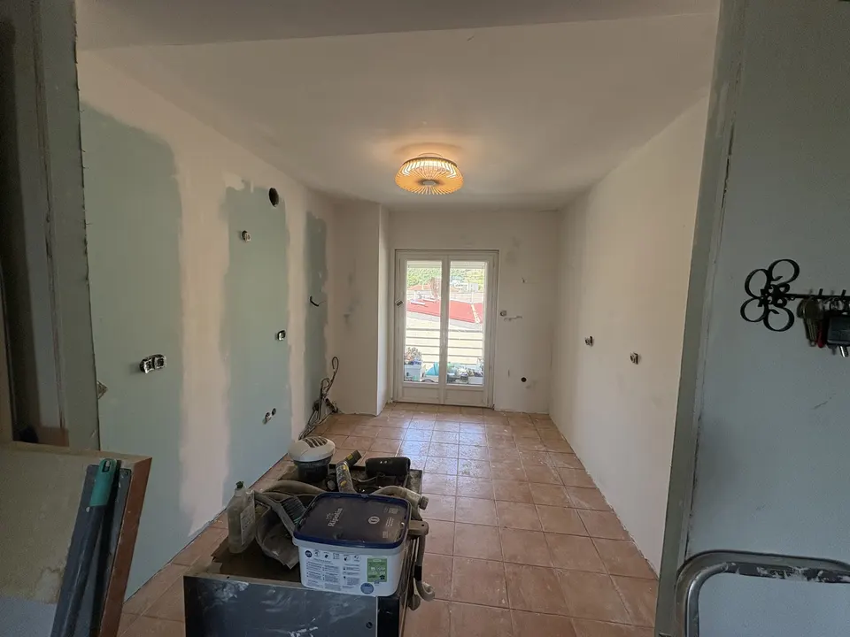 Murs en préparation, ancien carrelage encore en place, porte-fenêtre au fond