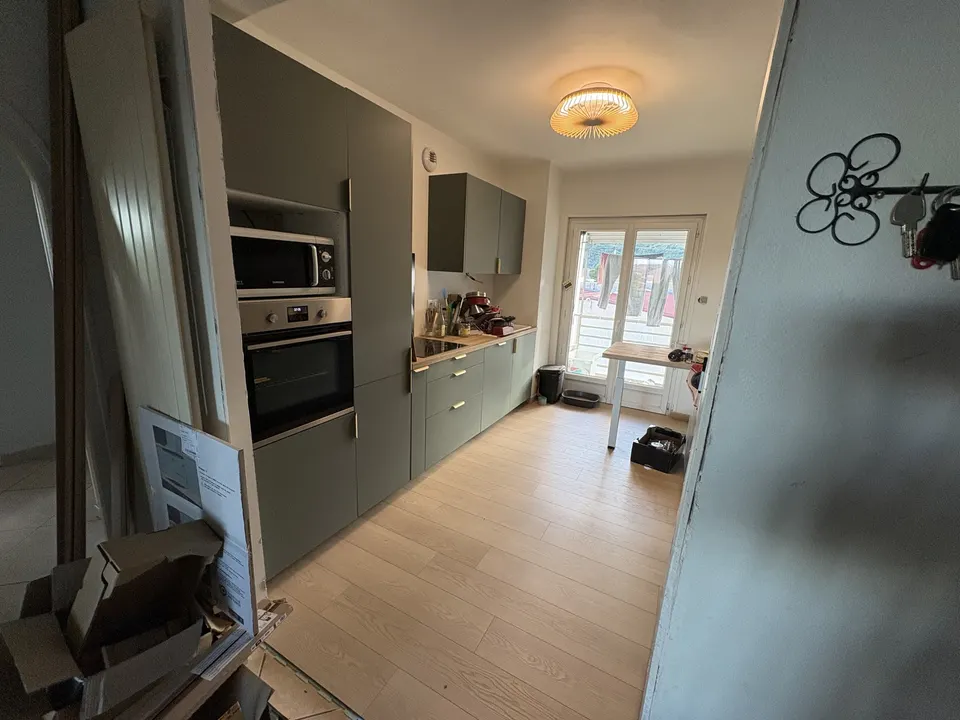 Colonnes avec four et micro-ondes, meubles verts posés, plan de travail bois