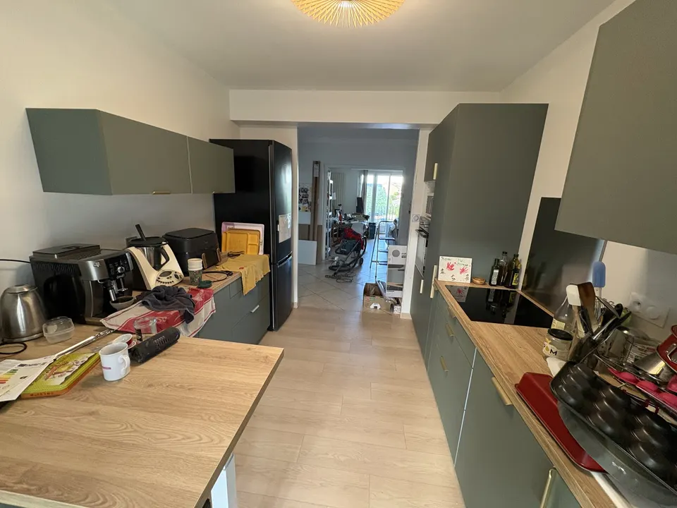 Cuisine aménagée en longueur, avec le séjour visible au fond