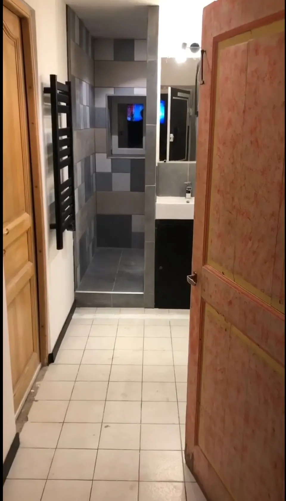 Salle de bain terminée : douche carrelée, vasque sur meuble noir et radiateur noir