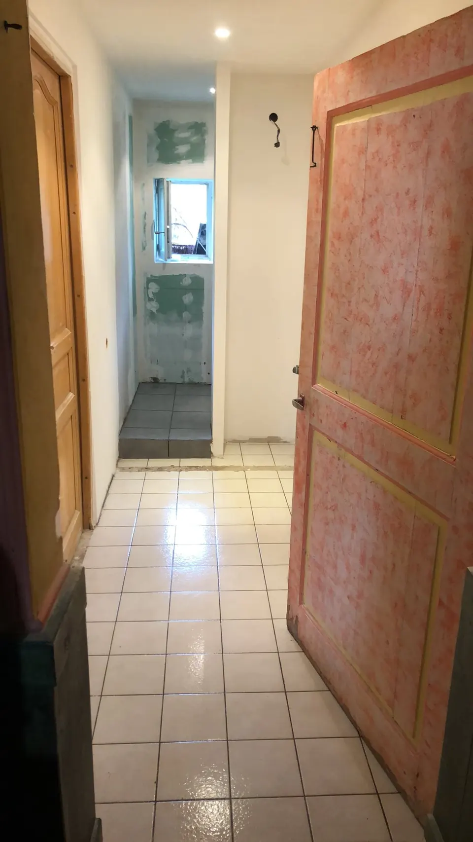 Couloir de la salle de bain, douche carrelée au fond, sol d'origine encore en place