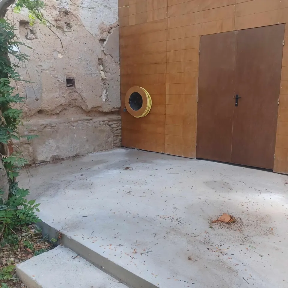 Avant la pose : dalle béton nue devant la porte en bois.